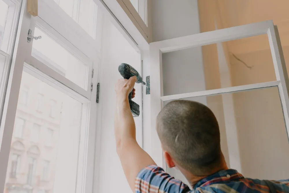 Handyman adjusting window fittings with a cordless screwdriver